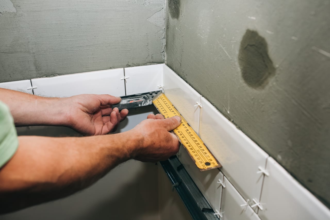 Carreleur posant du carrelage dans une salle de bain en rénovation